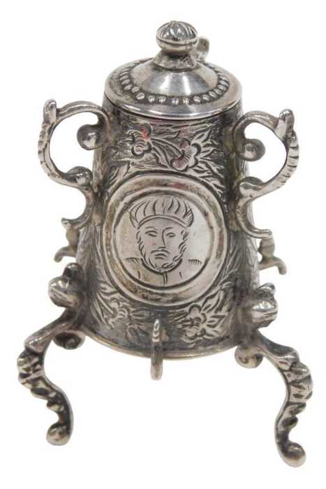 A 19thC miniature model of a samovar, heavily chased with panels set with figures on scroll feet,...