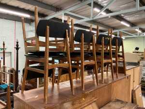 A set of eight teak dining chairs, each with leather backs and seats. The upholstery in this lot...