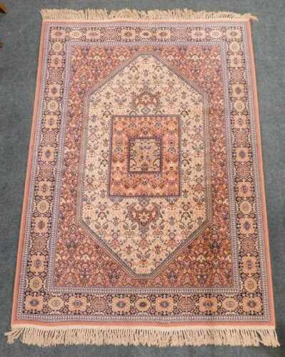 A 20th machine woven rug, the outer field with a geometric floral pattern, in cream, the inner...