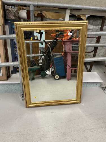 A gilt coloured hanging mirror, with bevelled glass.