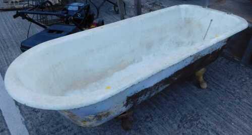 An early 20thC metal bath with iron feet, scroll edge and holes for taps.