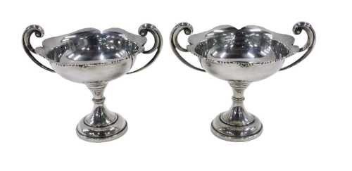 A pair of late Edward VII silver bonbon dishes, each with scroll handles, flared floral rims,...