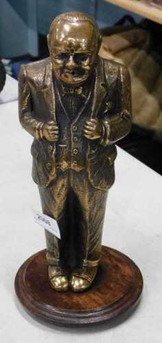 A standing brass figure of Winston Churchill, in jacket and trousers, on oak base, 26cm high.