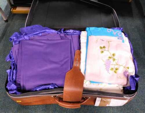 Various linen, some embroidered, floral examples, etc., in a travel case.