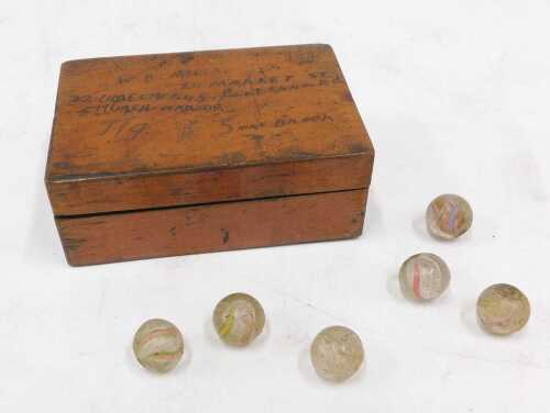 Various early 20thC marbles, probably French, in a treen box.