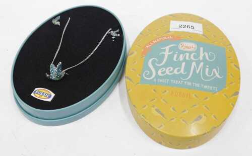 A fossil necklace and ear stud set, formed as birds, in a tin box.