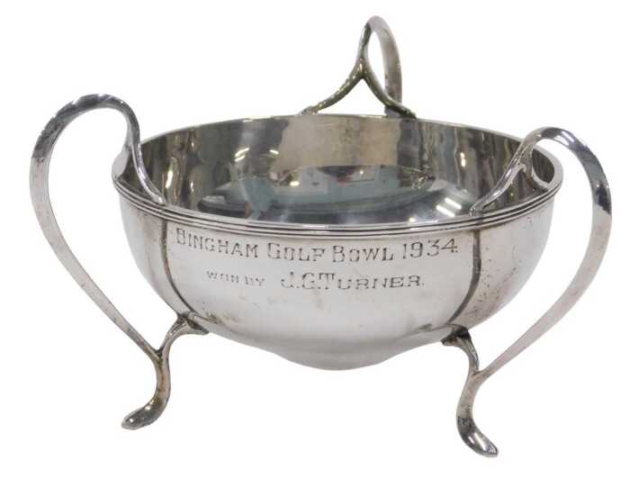 A George V silver three handled bowl, of shaped circular form, on hoof feet, marked Bingham Golf...