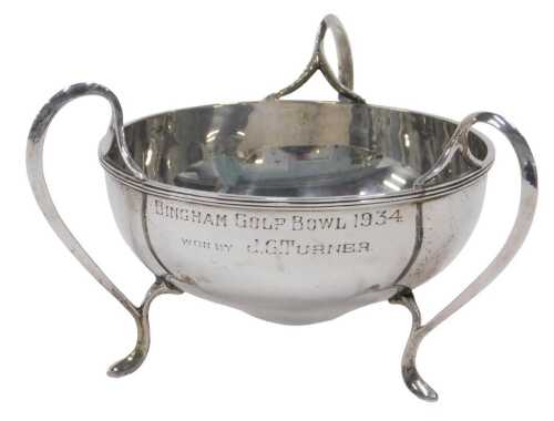 A George V silver three handled bowl, of shaped circular form, on hoof feet, marked Bingham Golf...