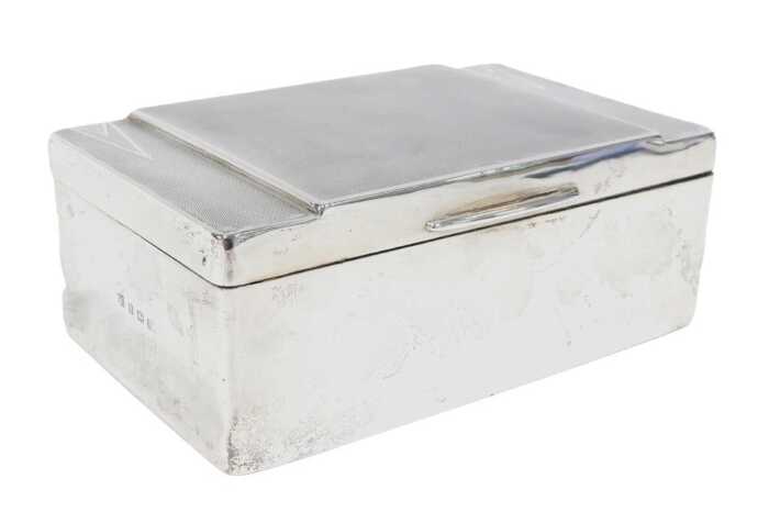 A George V Art Deco silver cigarette box, of oblong form, the hinged lid partially engine turned,...
