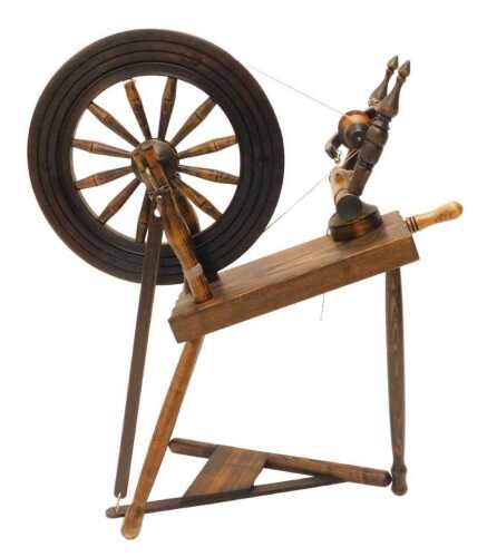A 20thC beech stained spinning wheel, the articulated wheel, on turned legs, 90cm high.