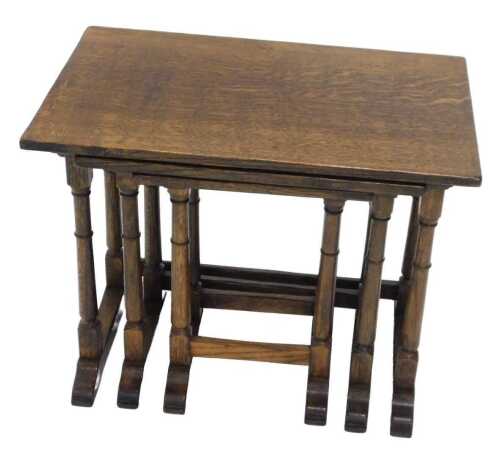 A nest of three 20thC oak tables, each of rectangular form, on turned legs terminating in scroll...