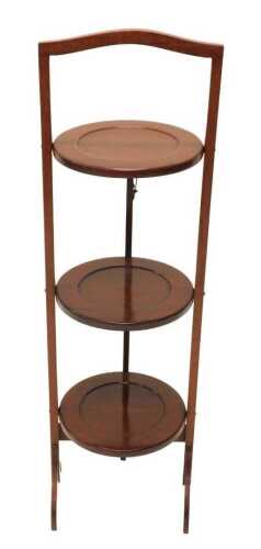 An early 20thC mahogany three tier cake stand, of articulated form, with arched handle and sabre...