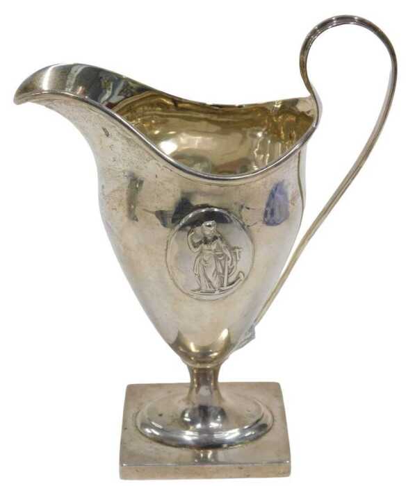An Edward VII silver cream jug, with strap handle, helmet shaped body, inverted stem and oval...