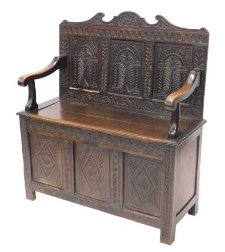 A 20thC oak Jacobean style monk's bench, the heavily carved three panelled back, with leaf and...