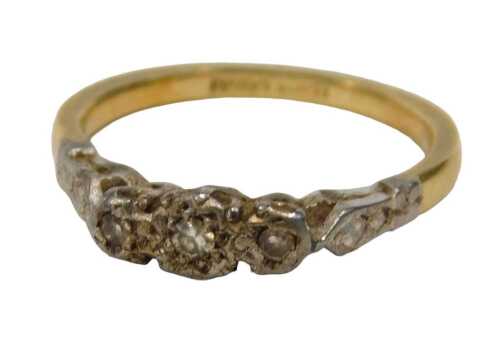 A three stone diamond dress ring, set with three tiny diamonds, in platinum setting, on a yellow...