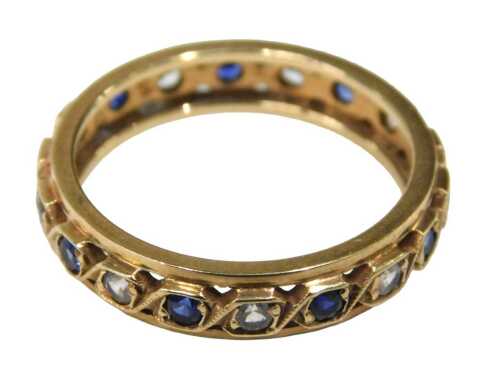 An eternity ring, set with sapphire and cz, yellow metal pierced design, with rubbed markings,...