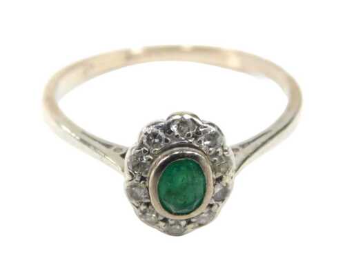 An emerald and diamond cluster ring, the central oval cut emerald 4.2mm x 3mm x 2.2mm approx, in...