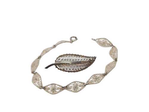 Two items of Eastern inspired jewellery, comprising a white metal leaf brooch, 4.5cm wide, and a...