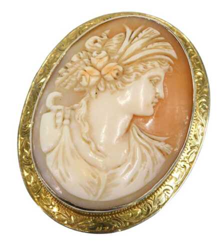 An early 20thC shell cameo brooch, depicting maiden looking dexter, with three roses, in a rub...