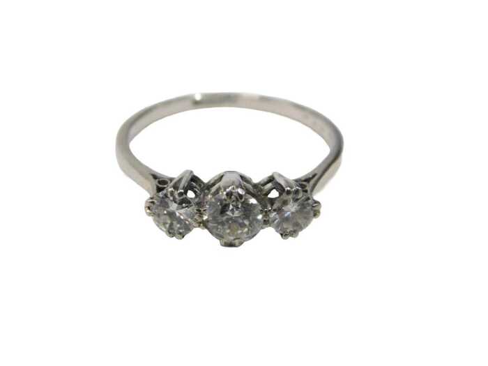 A three stone diamond dress ring, set with three round brilliant cut diamonds, the centre stone...