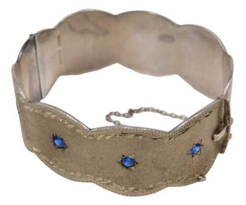 A silver half hinged bangle, with a brushed and etched petalated design, set with four blue...