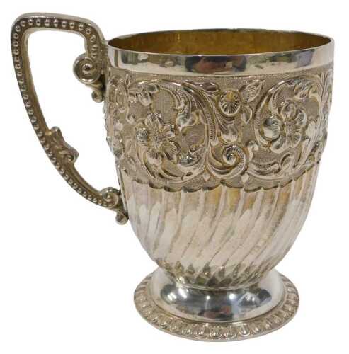 A Victorian silver mug, the heavily chased and repousse decorated bell shaped body, with shaped...