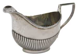 An Edward VII silver cream jug, of small proportion, with shaped spout, strapwork handle, part...