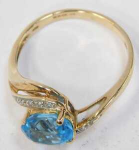 A 9ct gold QVC dress ring, centred with an oval cut aquamarine, and cz set shoulders, on a... - 2
