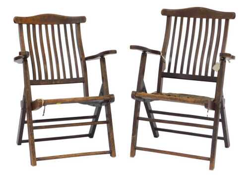 Two similar Edwardian mahogany campaign style folding chairs, each with a slatted back and solid...