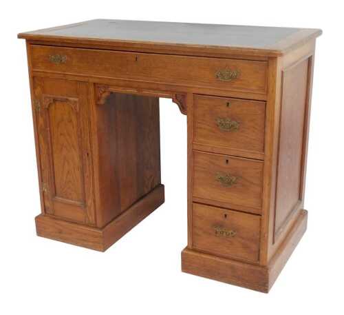 A late 19th/early 20thC oak kneehole desk, the rectangular top with a black leatherette insert...