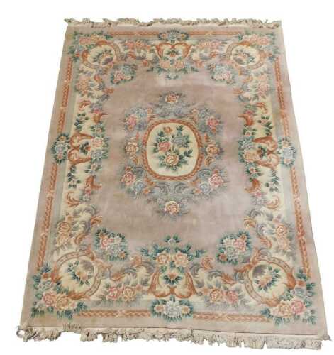 A large Chinese wool carpet, decorated with flowers, on an aubergine coloured ground with an...