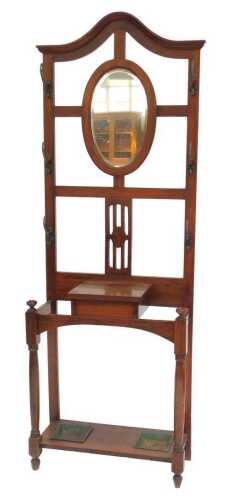 An Edwardian walnut hall stand, the arched top above a circular bevelled mirror plate, flanked...