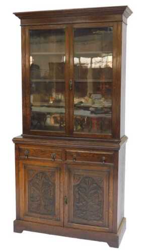An early 20thC oak cabinet bookcase, the top with a moulded pediment above two glazed doors...