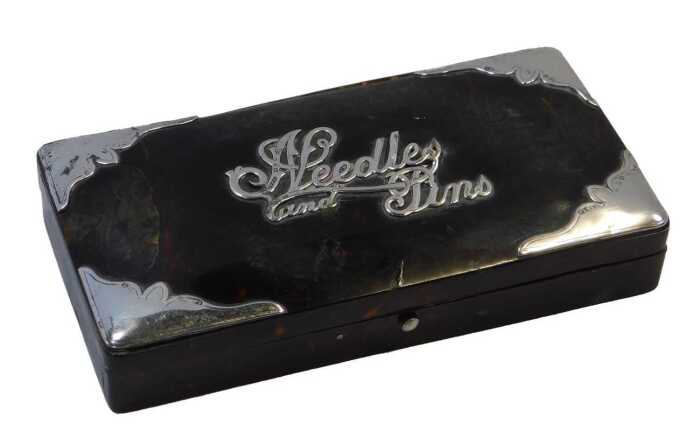 A tortoiseshell and silver-mounted dressing table box, titled Needles & Pins, with hinged lid,...