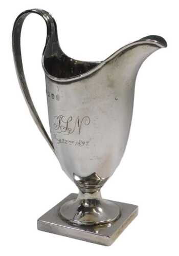 A late Victorian silver helmet shaped milk jug, engraved ISN and dated Aug 22nd 1897, raised on...