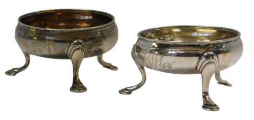 A pair of George III silver open salts, each with a beaded border, raised on three hoof feet,...