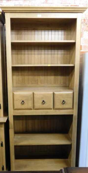 A lightwood finished bookcase, with two shelves over three drawers over two shelves, raised on...