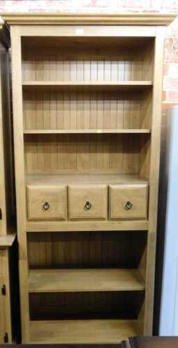 A lightwood finished bookcase, with two shelves over three drawers over two shelves, raised on...