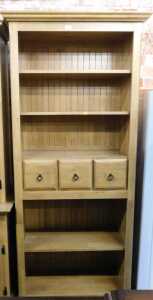 A lightwood finished bookcase, with two shelves over three drawers over two shelves, raised on...