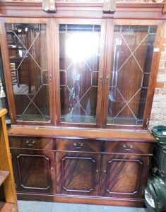 A mahogany veneered display cabinet, of three astragal glazed doors over three drawers above...