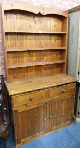 A pine dresser, with plate rack over base unit of two drawers over two cupboard doors, raised on...