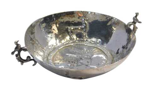 A Peruvian twin-handled bowl, the interior embossed centrally with the sun rising over the...