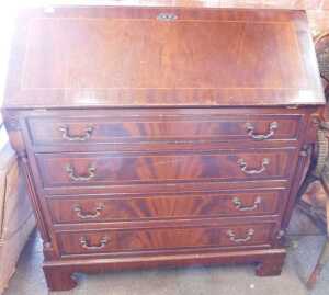 A mahogany veneered fall front bureau, fall over four long drawers, flanked by reeded columns,...