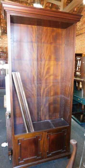 A large mahogany bookcase, with four shelves to top over two panelled doors, raised on bracket...