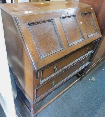 An oak bureau, with fall front, over two drawers, raised on barley twist supports joined by...