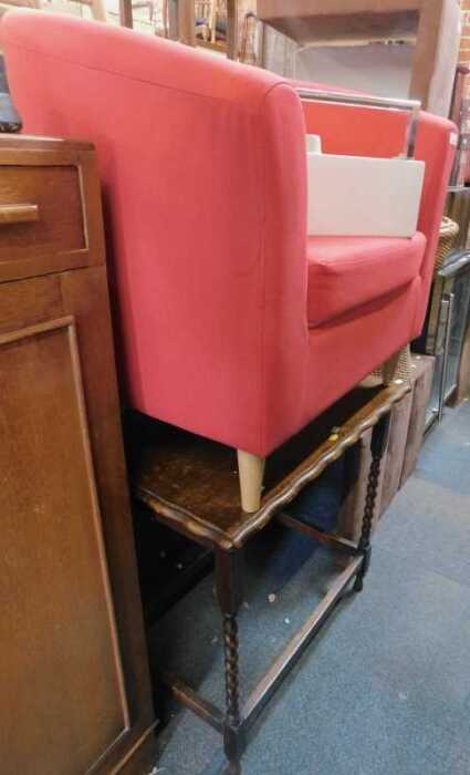 A red upholstered tub chair, a square topped occasional table on barley twist supports joined by...