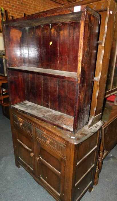 A dark oak dresser, with a plate rack over two drawers above two cupboard doors, raised on...