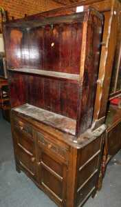 A dark oak dresser, with a plate rack over two drawers above two cupboard doors, raised on...