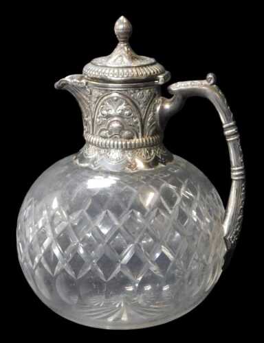 A late Victorian silver-mounted cut-glass globular claret jug, the mount heavily decorated with...