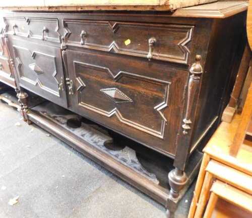 An oak sideboard, with two drawers over two doors, with applied decoration, stretchers below, on...